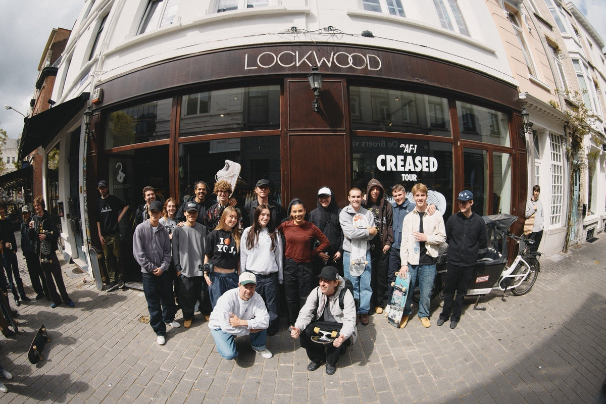 A large group of people posing with skateboards outside the Lockwood storefront, which features an 'AF-1 CREASED TOUR' sign on the window.