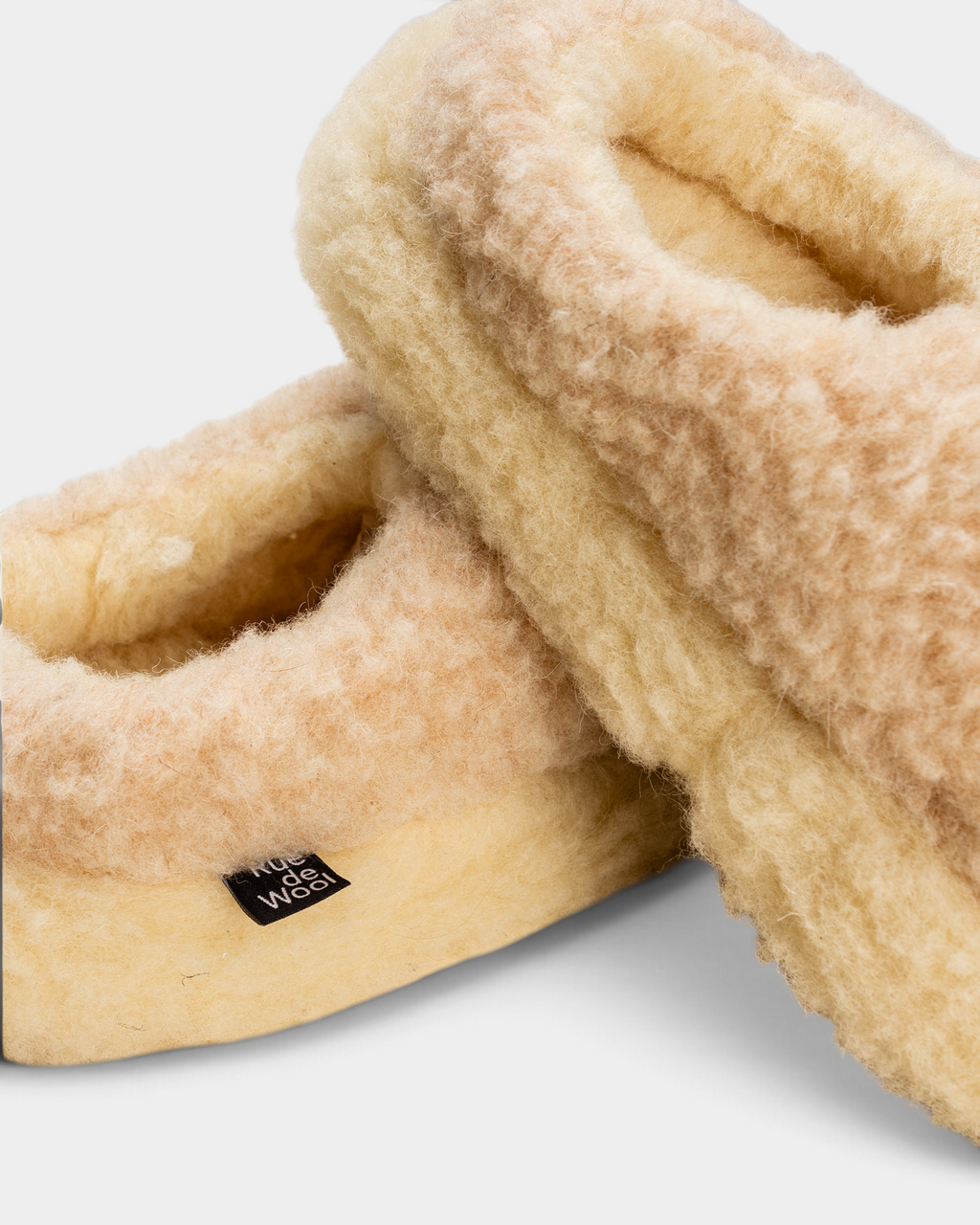 Close-up of the desert brown curly wool and natural rim of the Rue De Wool The Nordic Low, with its small woven label