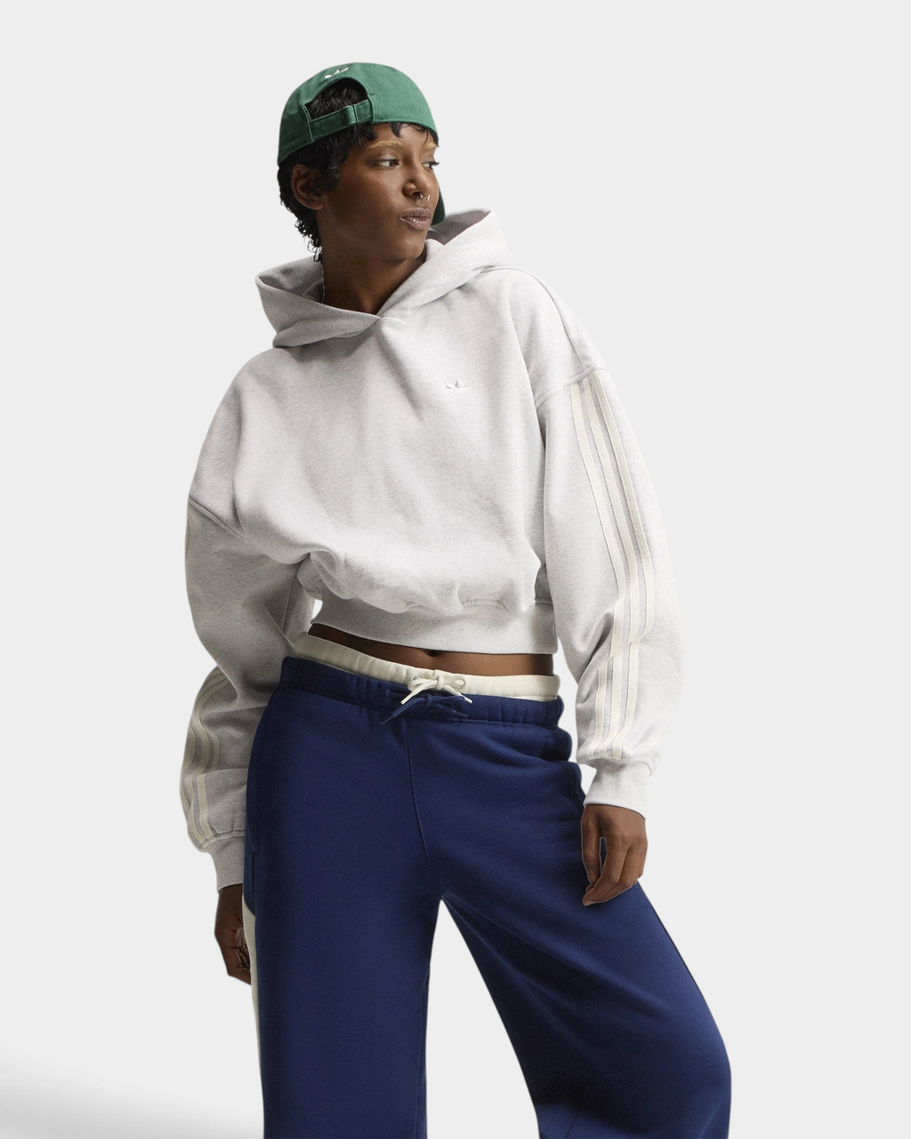 Lockwood Avenue adidas adiSignature 3-Stripes Hoodie in light grey heather on a model with a green cap and navy sweatpants, front view with the hood down