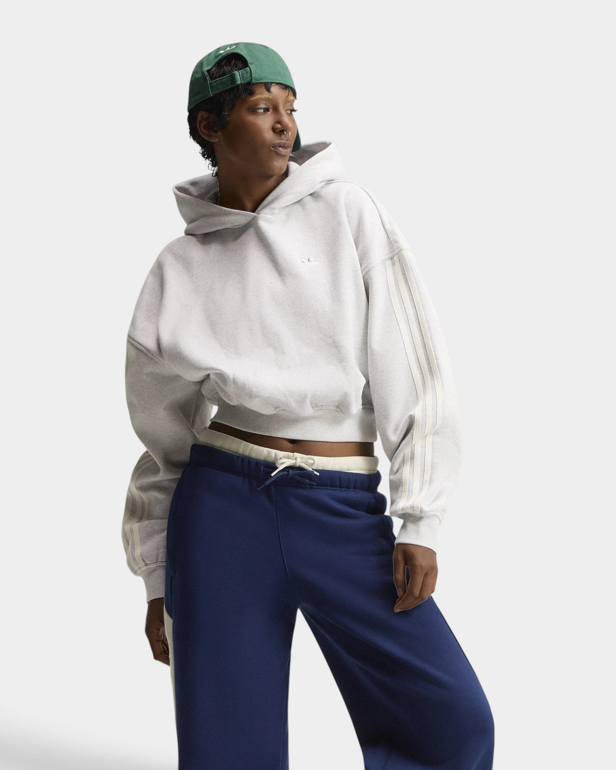 Lockwood Avenue adidas adiSignature 3-Stripes Hoodie in light grey heather on a model with a green cap and navy sweatpants, front view with the hood down