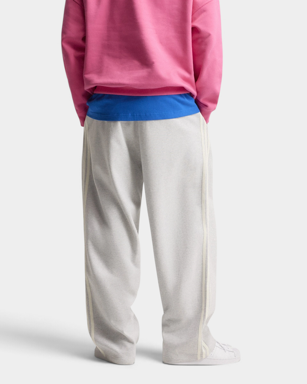 Lockwood Avenue adidas adiSignature 3-Stripes Open Hem Sweatpants in light grey heather seen from behind, loose legs over white sneakers