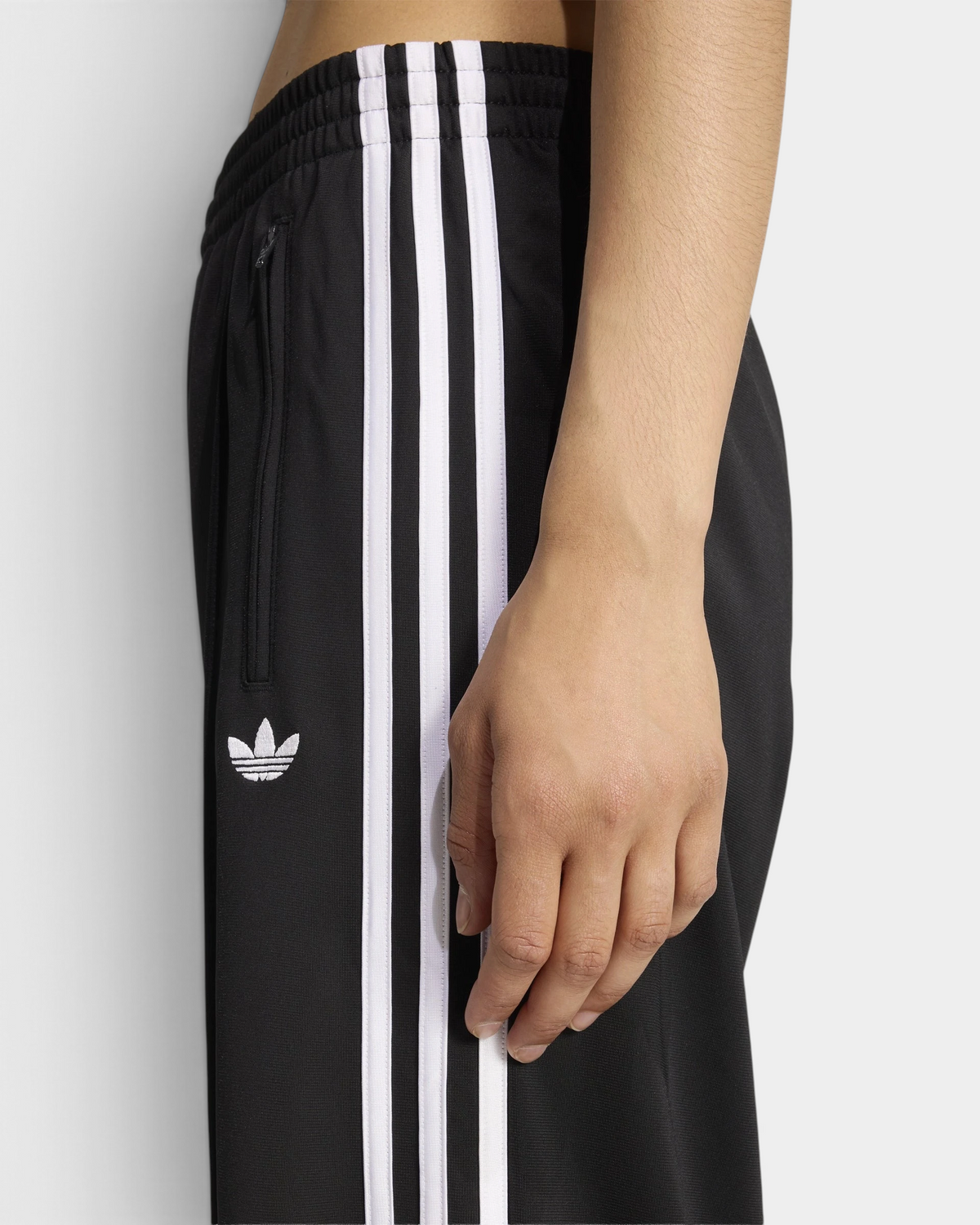 Lockwood Avenue adidas Firebird Loose Track Pants close up of the waistband and hip, elastic waist, zip pocket, white Trefoil and 3-Stripes