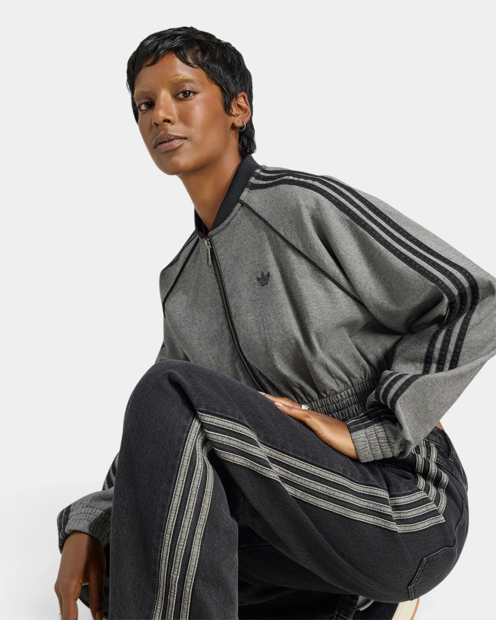 Lockwood Avenue adidas SST Denim Track Top in light grey denim, crouching pose showing the black 3-Stripes over the shoulder and sleeve