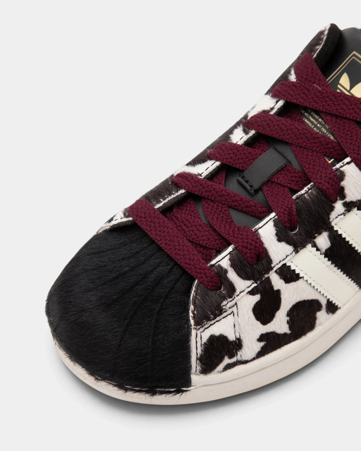 Lockwood Avenue adidas Superstar II W shoe close up, the black rubber shell toe against the animal-print upper and the maroon laces