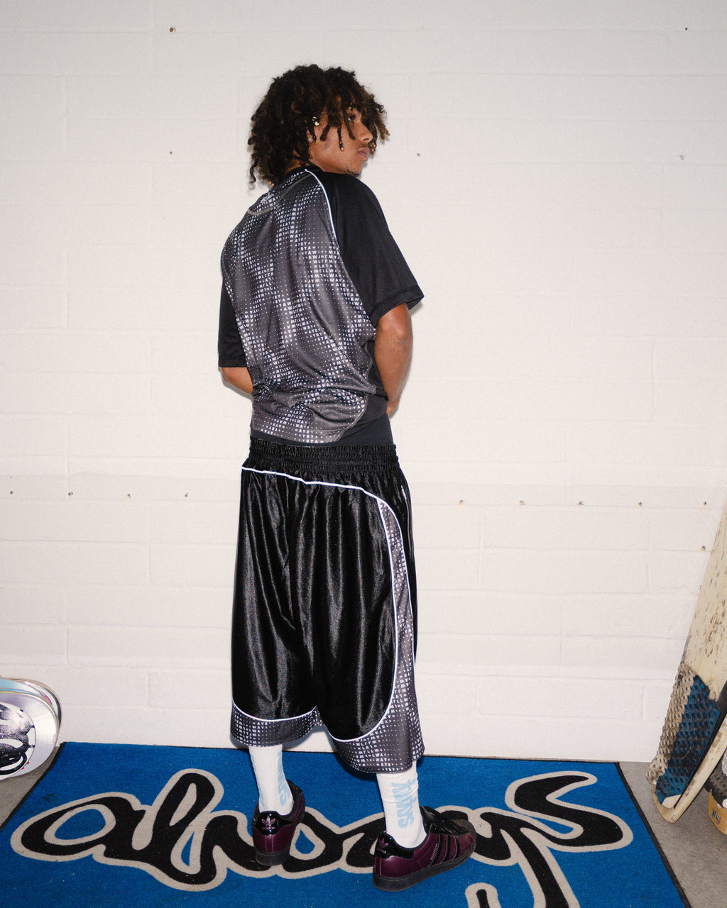 Lockwood Avenue ADWYSD Cross Plaid Shirt in Black/Grey worn by a model seen from behind, with wide shiny black shorts