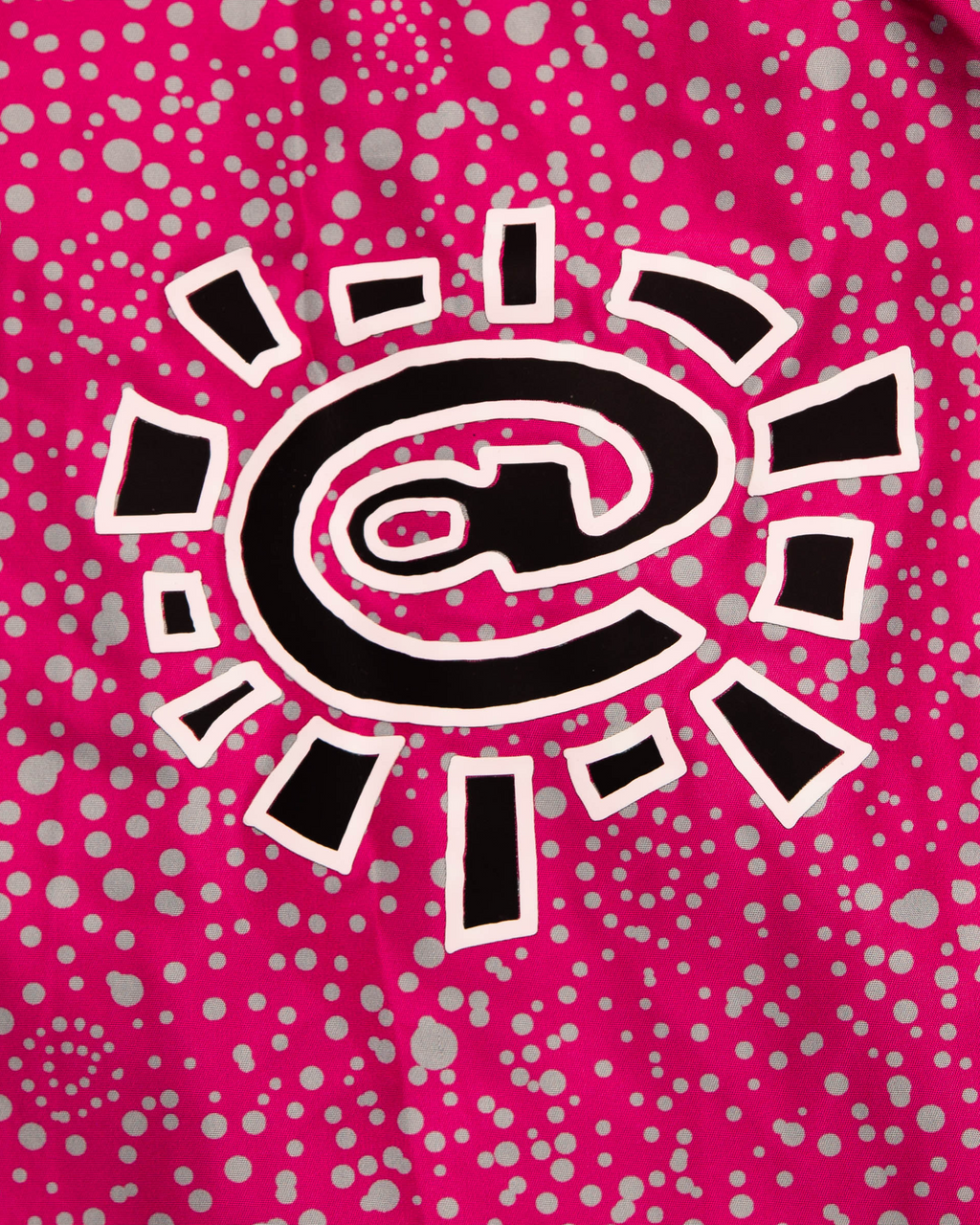 Lockwood Avenue ADWYSD Dotted Bandemic Jacket in Fuchsia, close-up of the black and white @ sun logo on the dot print