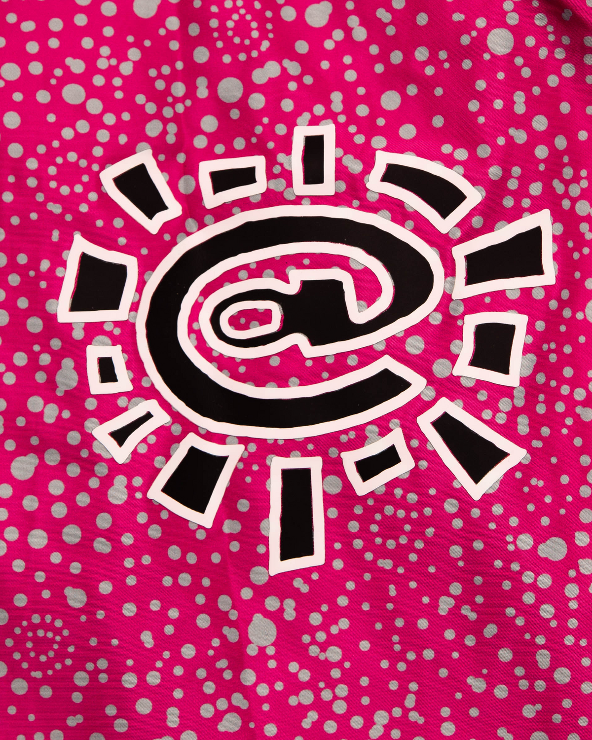 Lockwood Avenue ADWYSD Dotted Bandemic Jacket in Fuchsia, close-up of the black and white @ sun logo on the dot print