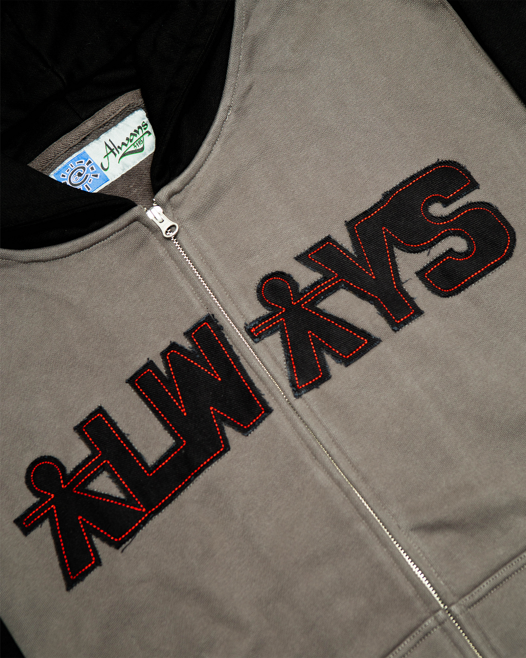 Lockwood Avenue ADWYSD Human Applique Zip-Up Hoodie in Black, close-up of the black ALWAYS appliqué with red stitching beside the zip