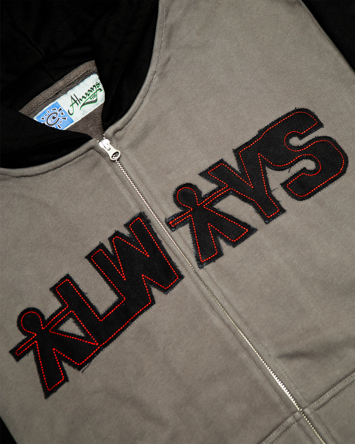 Lockwood Avenue ADWYSD Human Applique Zip-Up Hoodie in Black, close-up of the black ALWAYS appliqué with red stitching beside the zip
