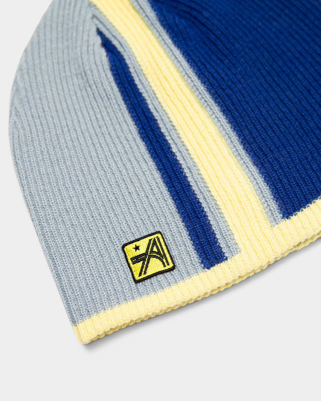 Lockwood Avenue ADWYSD Stripe Beanie in Blue/Yellow, close-up of the yellow stripe, ribbed knit and the woven logo patch