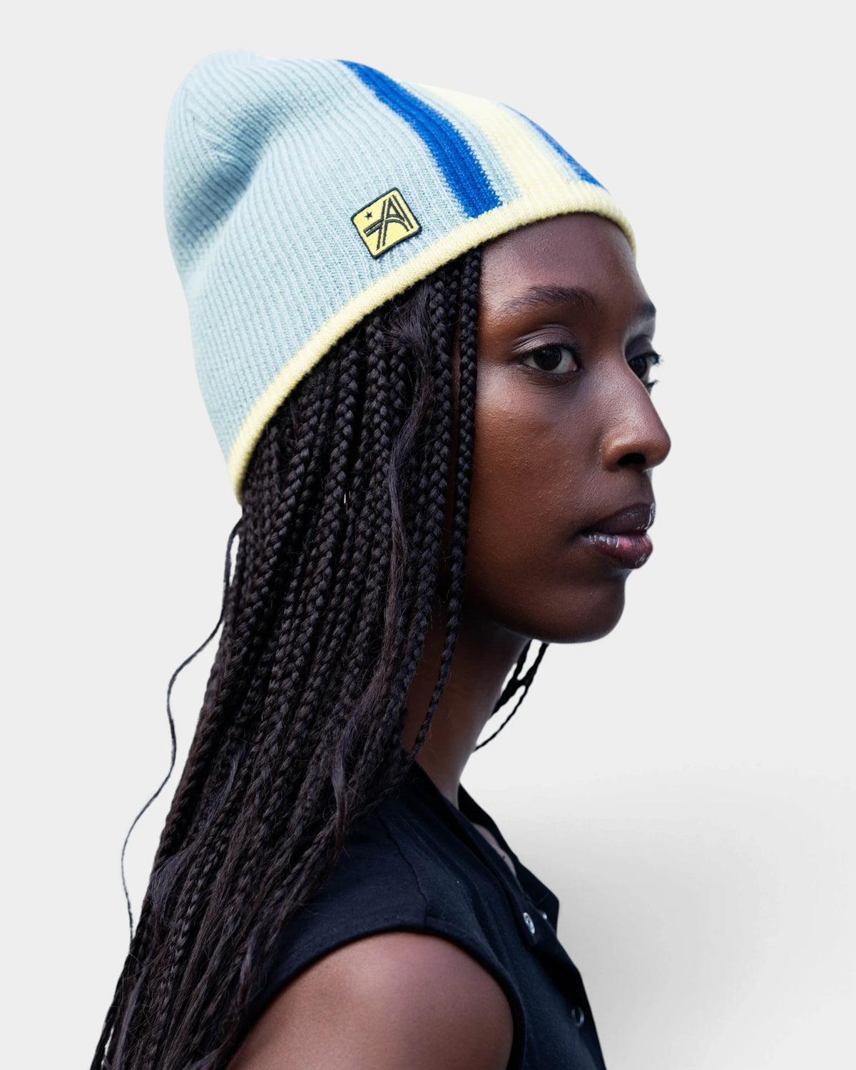 Lockwood Avenue ADWYSD Stripe Beanie in Blue/Yellow, worn by a model in profile, pale blue knit with a royal blue stripe and cream trim
