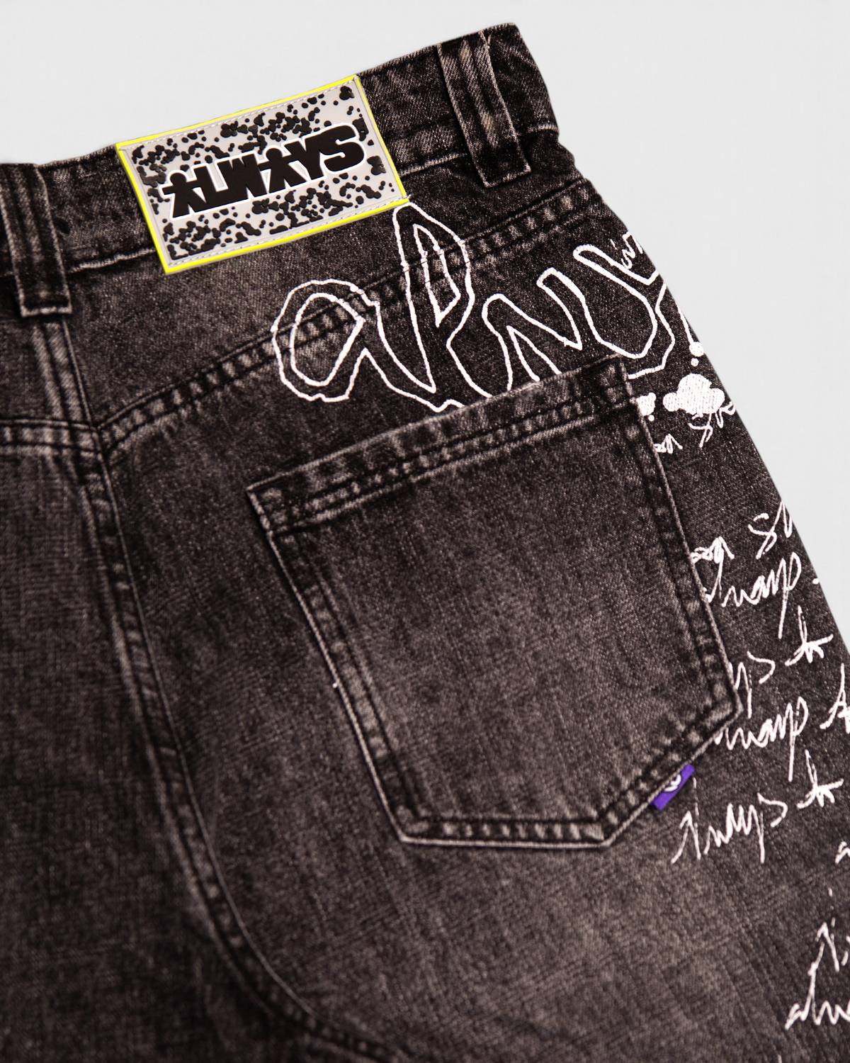 Lockwood Avenue ADWYSD Waza Jeans in Washed Black, close-up of the woven ALWAYS patch and white script beside the back pocket