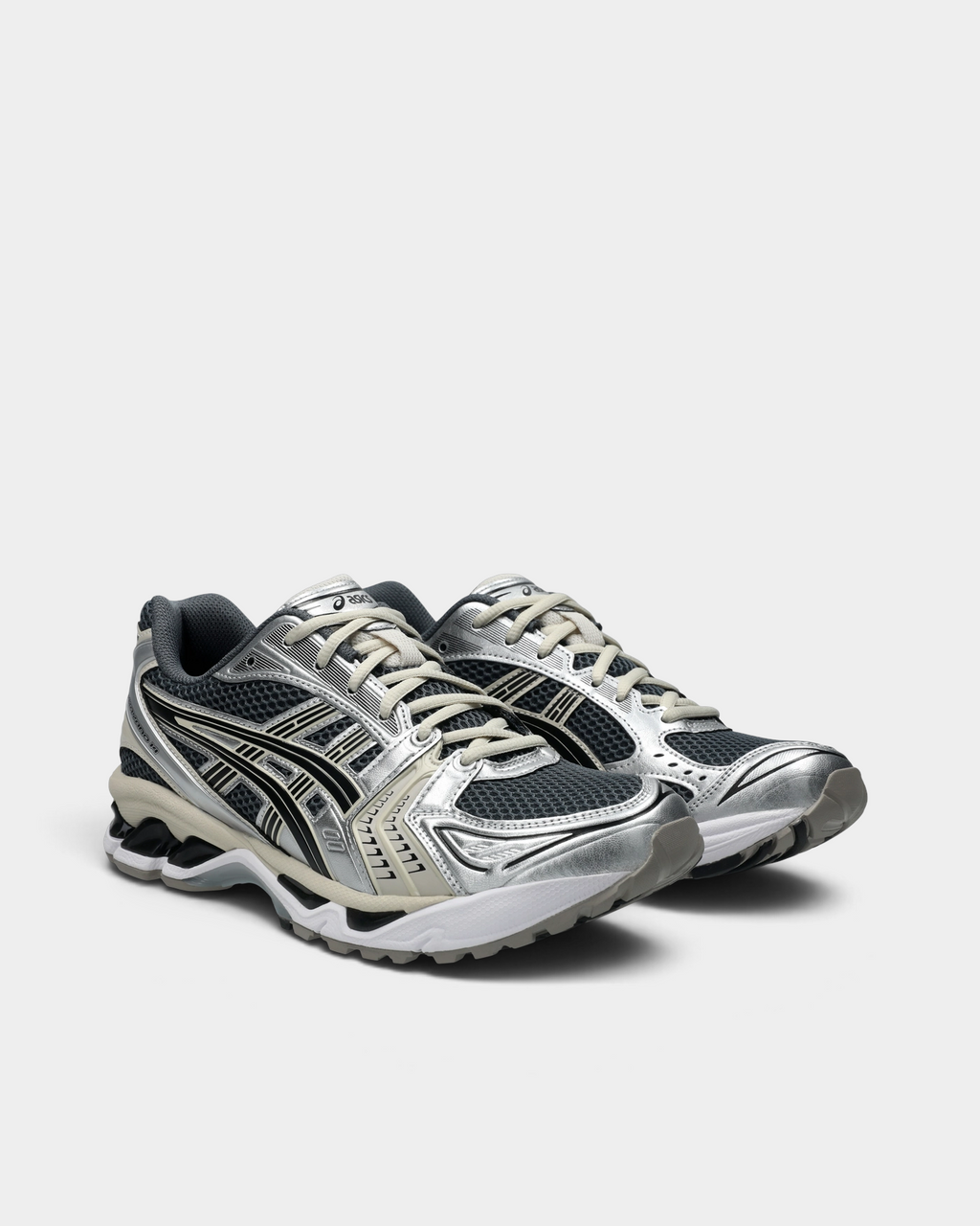 Asics GEL-Kayano 14 Shoes in Carrier Grey/Black, pair at a three-quarter front angle showing the silver toe overlays, graphite mesh, cream laces and the white sole