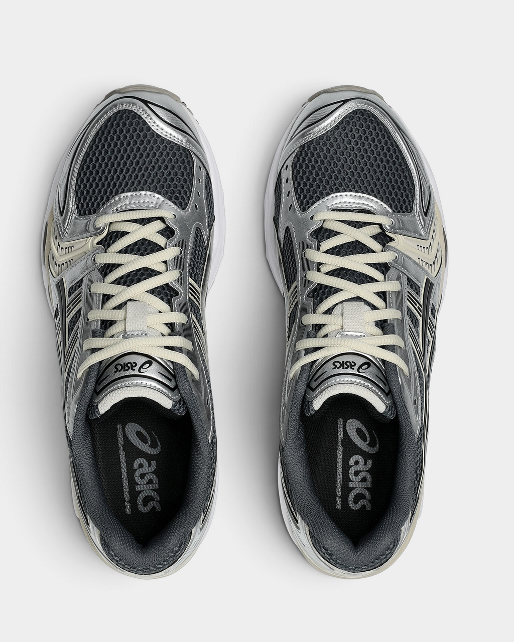Asics GEL-Kayano 14 Shoes in Carrier Grey/Black, pair from above with cream laces over graphite mesh and silver side panels, and the ASICS logo on the insoles