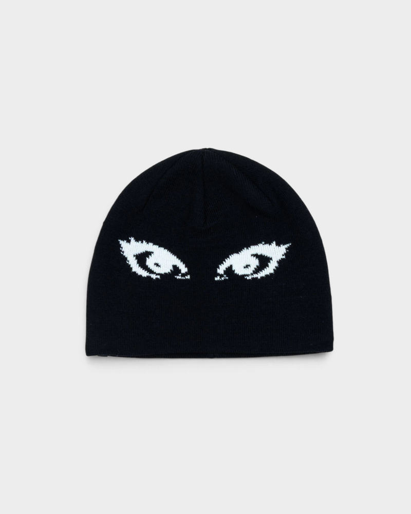 Lockwood Avenue Beyond Medals Jacquard Beanie Eyes in black, laid flat, a close-fitting beanie with a pair of white lashed eyes knitted across the front
