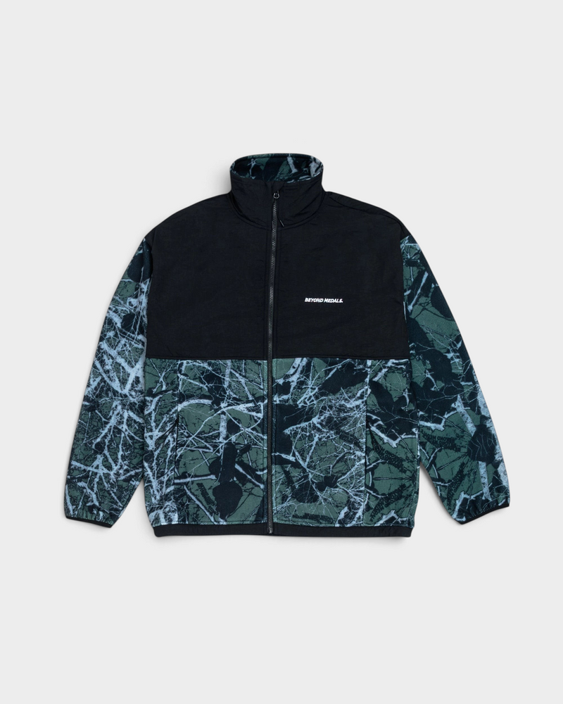 Lockwood Avenue Beyond Medals Tech Fleece Jacket in black, laid flat, a black nylon collar and upper body above a dark green branch-print fleece with a white embroidered logo on the chest