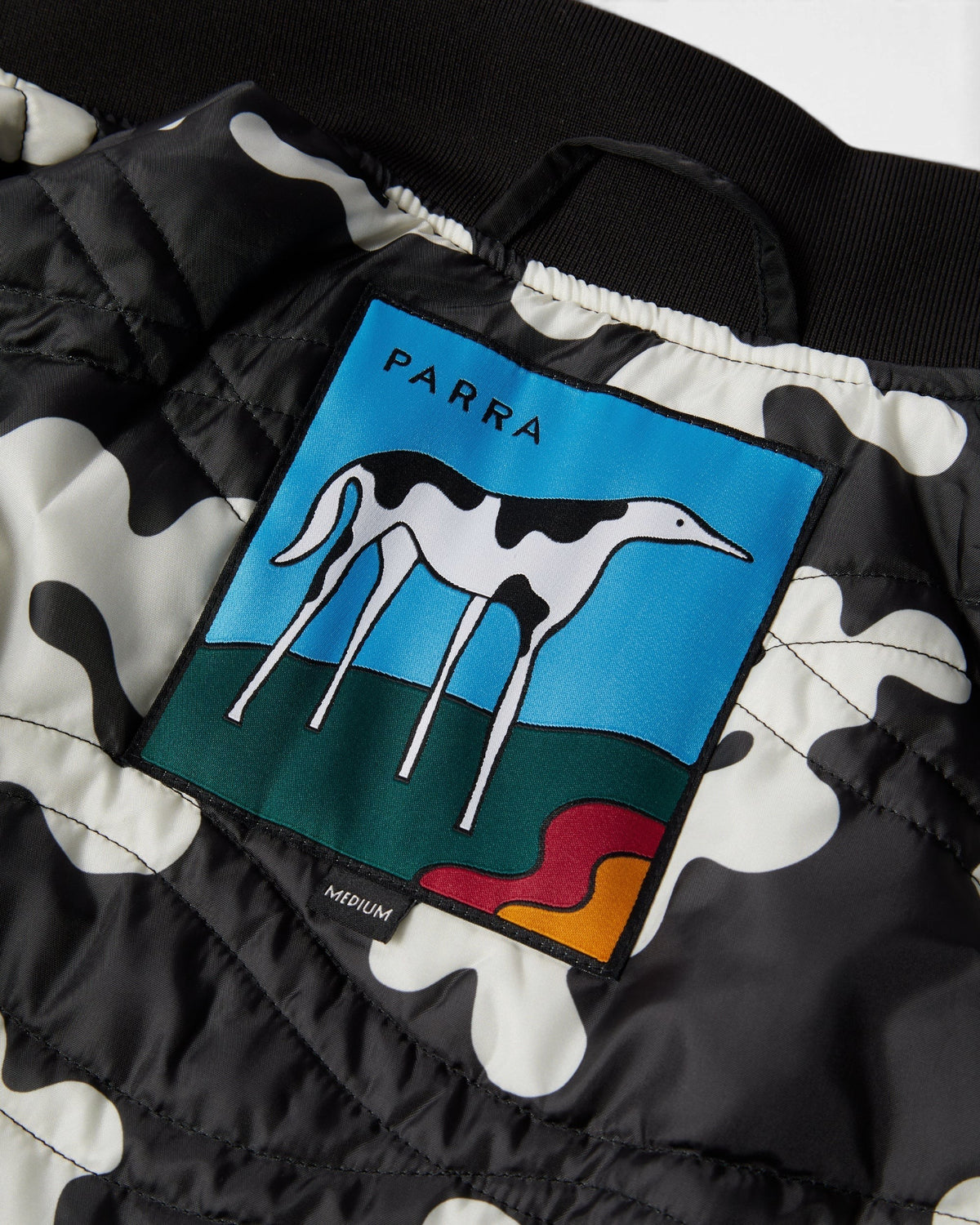 by Parra Club Not 1976 Satin Bomber Jacket - Black, close-up of the Parra dog patch on the lining