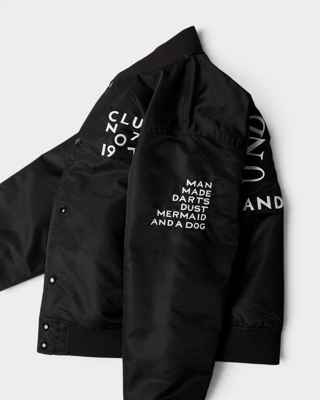 by Parra Club Not 1976 Satin Bomber Jacket - Black, angled view showing the sleeve embroideries