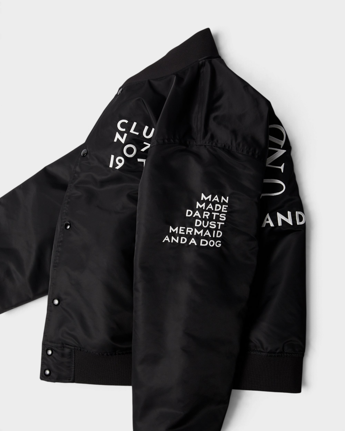 by Parra Club Not 1976 Satin Bomber Jacket - Black, angled view showing the sleeve embroideries