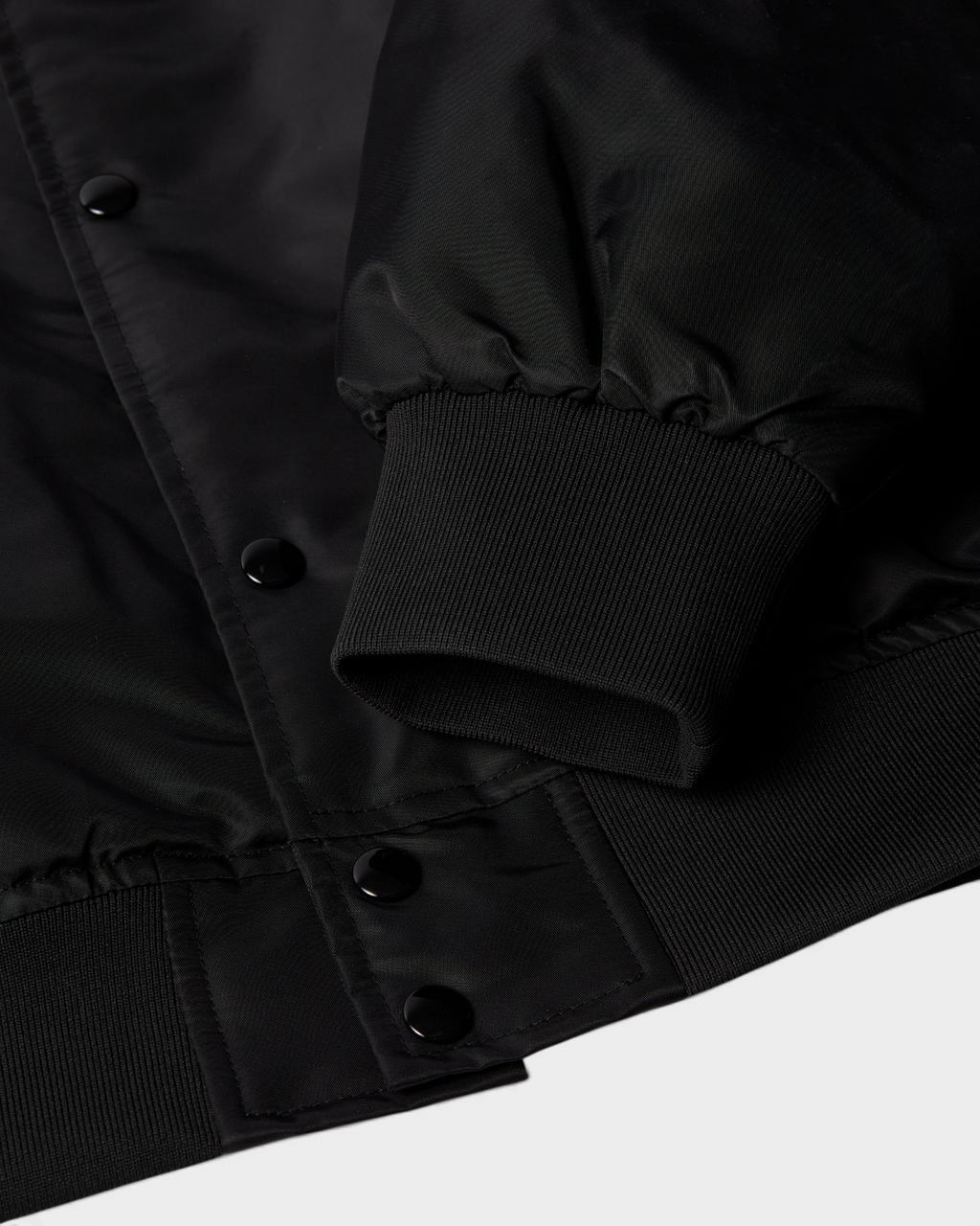 by Parra Club Not 1976 Satin Bomber Jacket - Black, close-up of the ribbed cuff and snap buttons