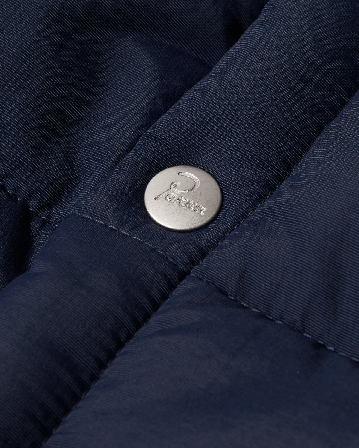 by Parra New System Puffer Vest - Navy Blue, close-up of a Parra snap button