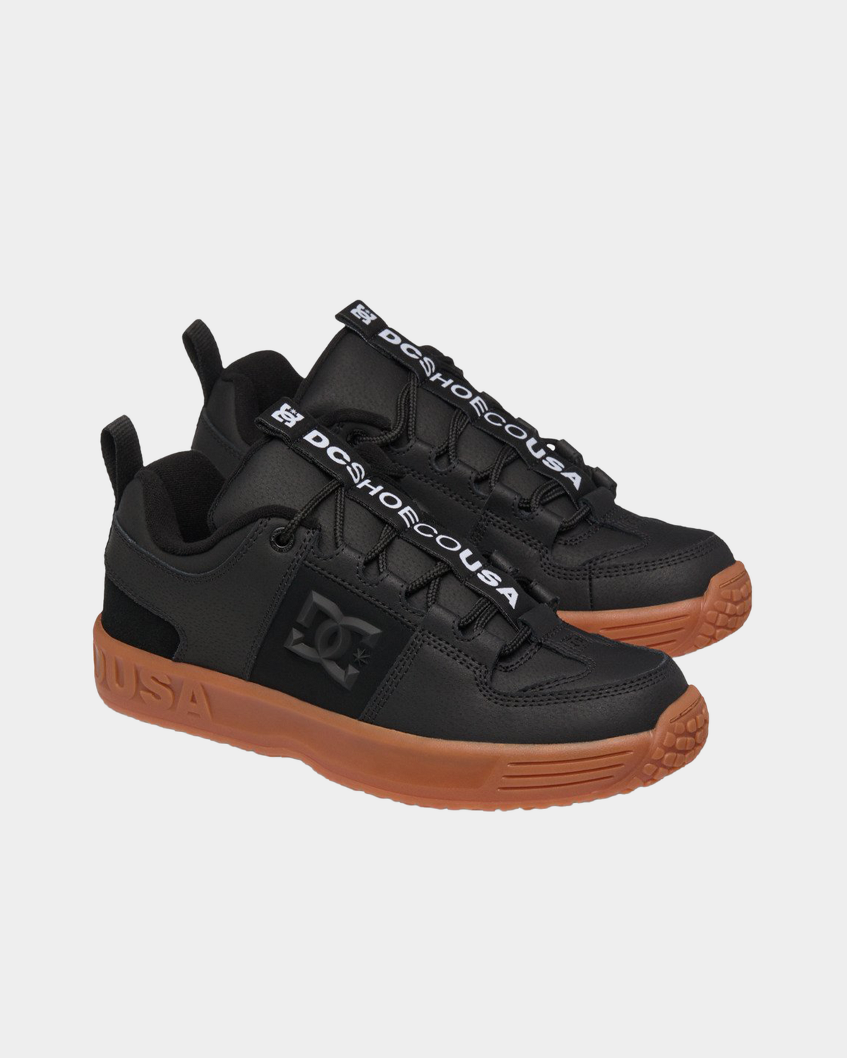 Pair of DC Lynx OG black skate shoes at a three-quarter angle, showing the DC SHOE CO USA lace tape and gum outsoles