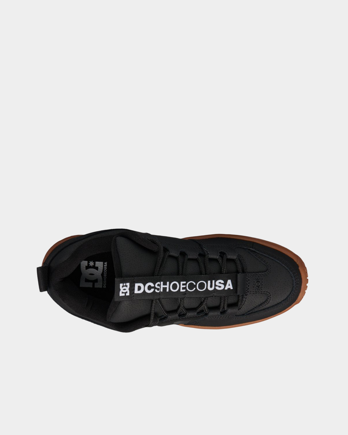 DC Lynx OG black skate shoe from above, showing the DC SHOE CO USA tongue strap, black laces and perforated leather panels