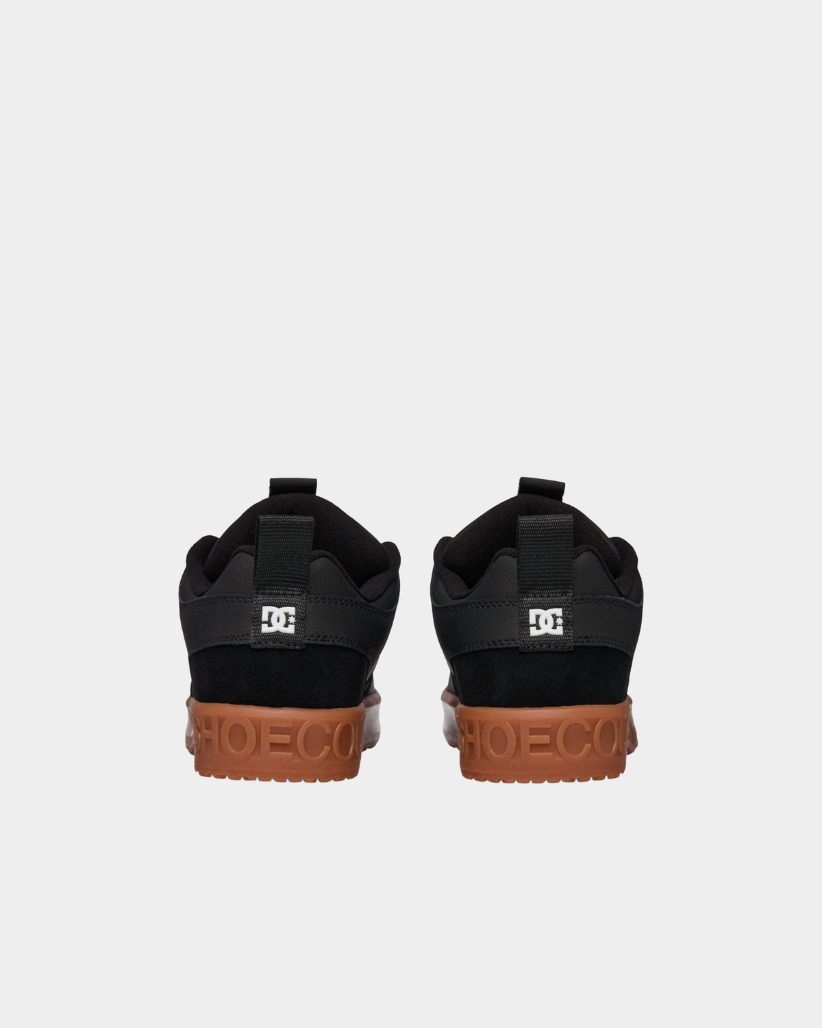 Pair of DC Lynx OG black skate shoes from behind, showing the black suede heel panels, DC heel logos and gum midsoles