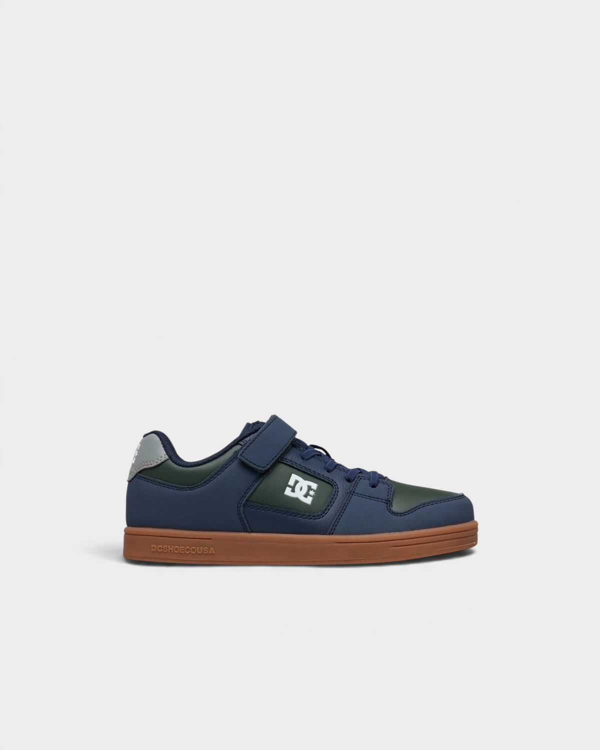 Lockwood Avenue DC Manteca 4 kids skate shoes in navy and green, side view with the velcro strap, white DC logo and gum rubber cupsole