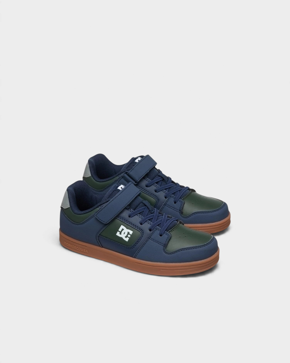 Lockwood Avenue DC Manteca 4 kids skate shoes in navy and green, angled front view of the pair with elastic laces and velcro straps