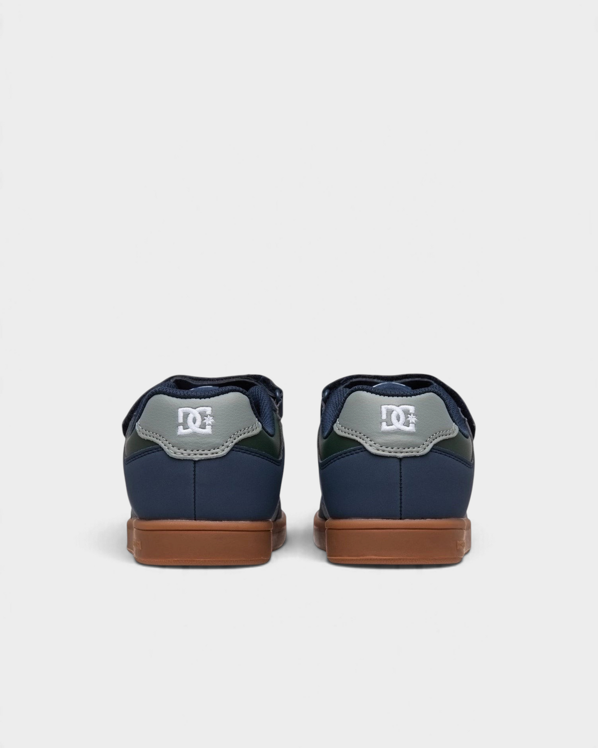 Lockwood Avenue DC Manteca 4 kids skate shoes in navy and green, rear view of the pair showing the grey heel tabs with white DC logos