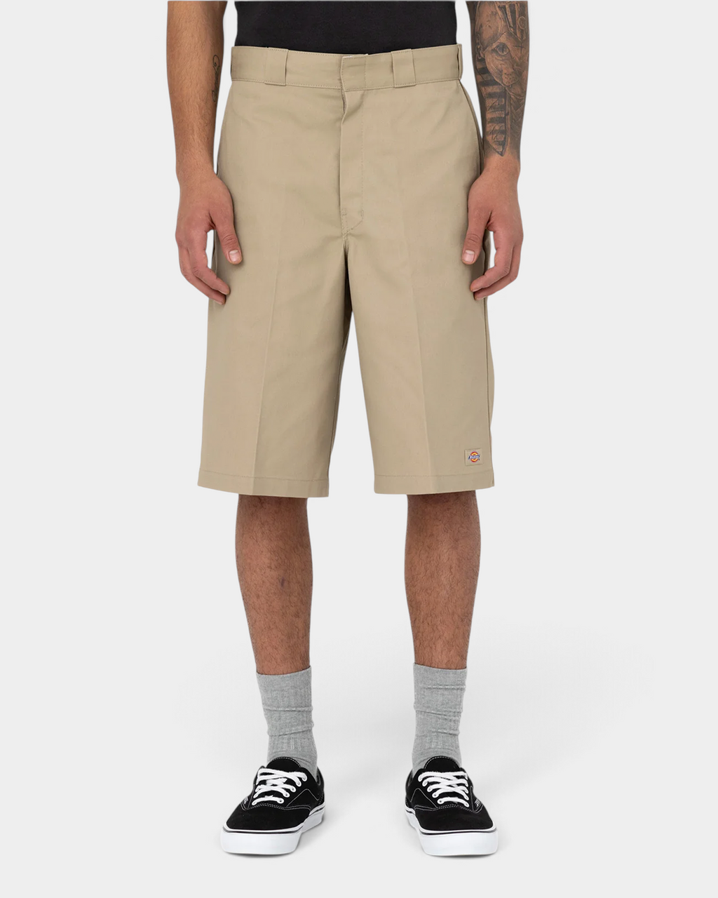 Lockwood Avenue model wearing stone Dickies 13 inch loose fit work shorts with grey socks and black skate shoes, front view