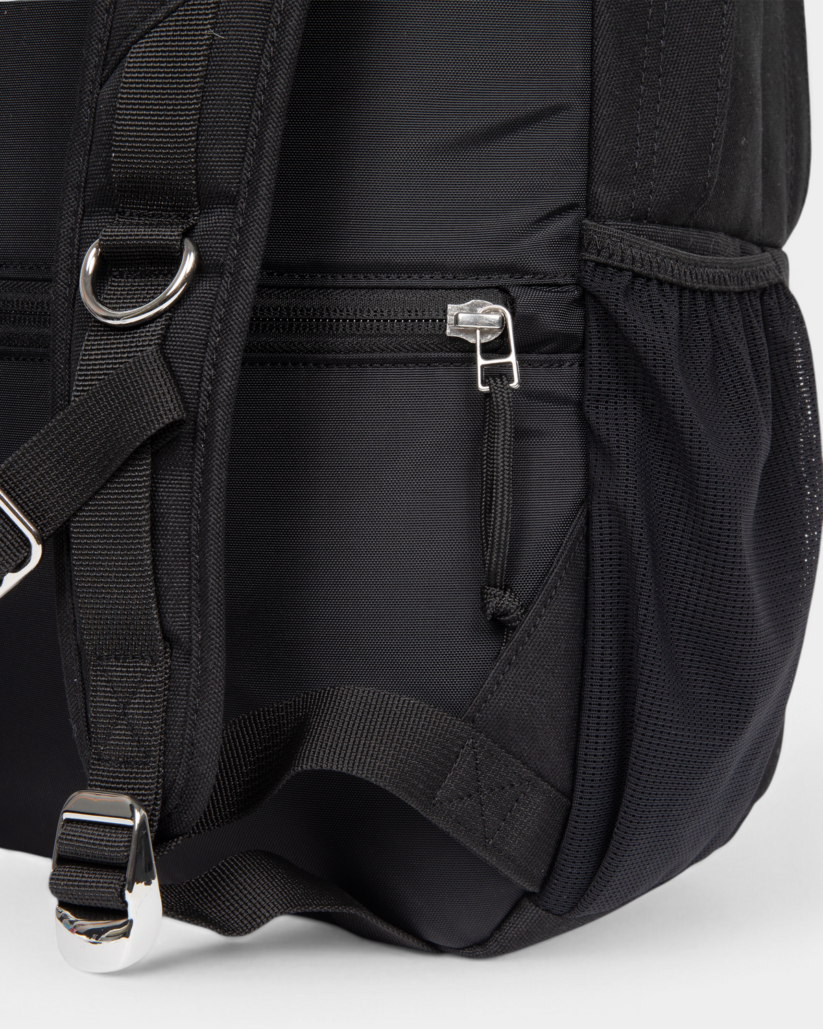 Close up of the lower side of the Eastpak x Dime Getter Backpack in Dime Black, showing the zipped side pocket and the webbing strap running into the mesh pocket