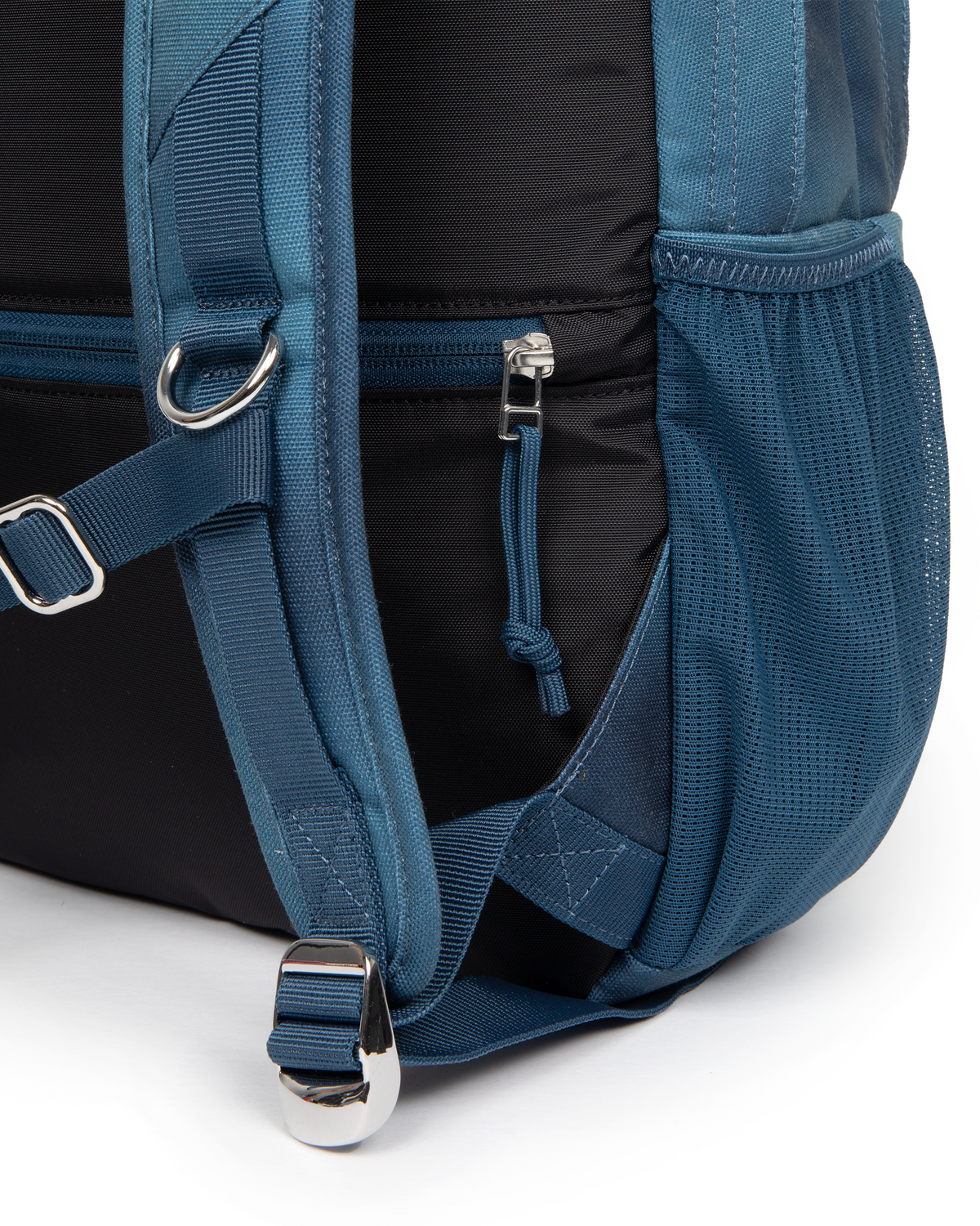 Close up of the lower side of the Eastpak x Dime Getter Backpack in Dime Navy, showing the zipped side pocket and the webbing strap running into the mesh pocket