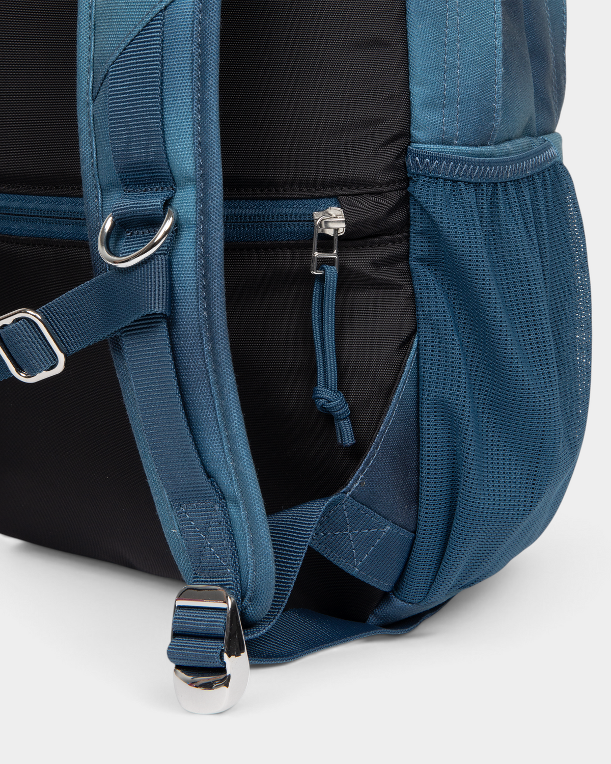 Close up of the lower side of the Eastpak x Dime Getter Backpack in Dime Navy, showing the zipped side pocket and the webbing strap running into the mesh pocket