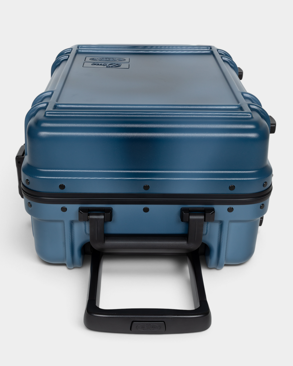Eastpak x Dime Resist'R Case S in Dime Navy laid on its back with the telescopic handle extended toward the camera, showing the riveted frame, the ribbed top panel and the moulded top and side grab handles