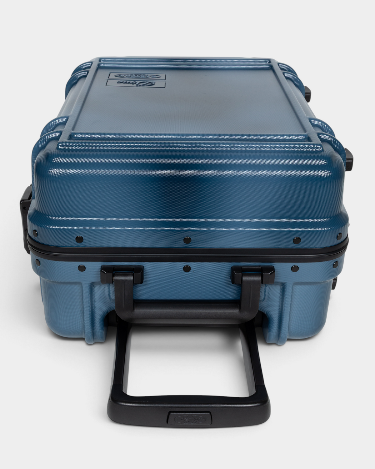 Eastpak x Dime Resist'R Case S in Dime Navy laid on its back with the telescopic handle extended toward the camera, showing the riveted frame, the ribbed top panel and the moulded top and side grab handles