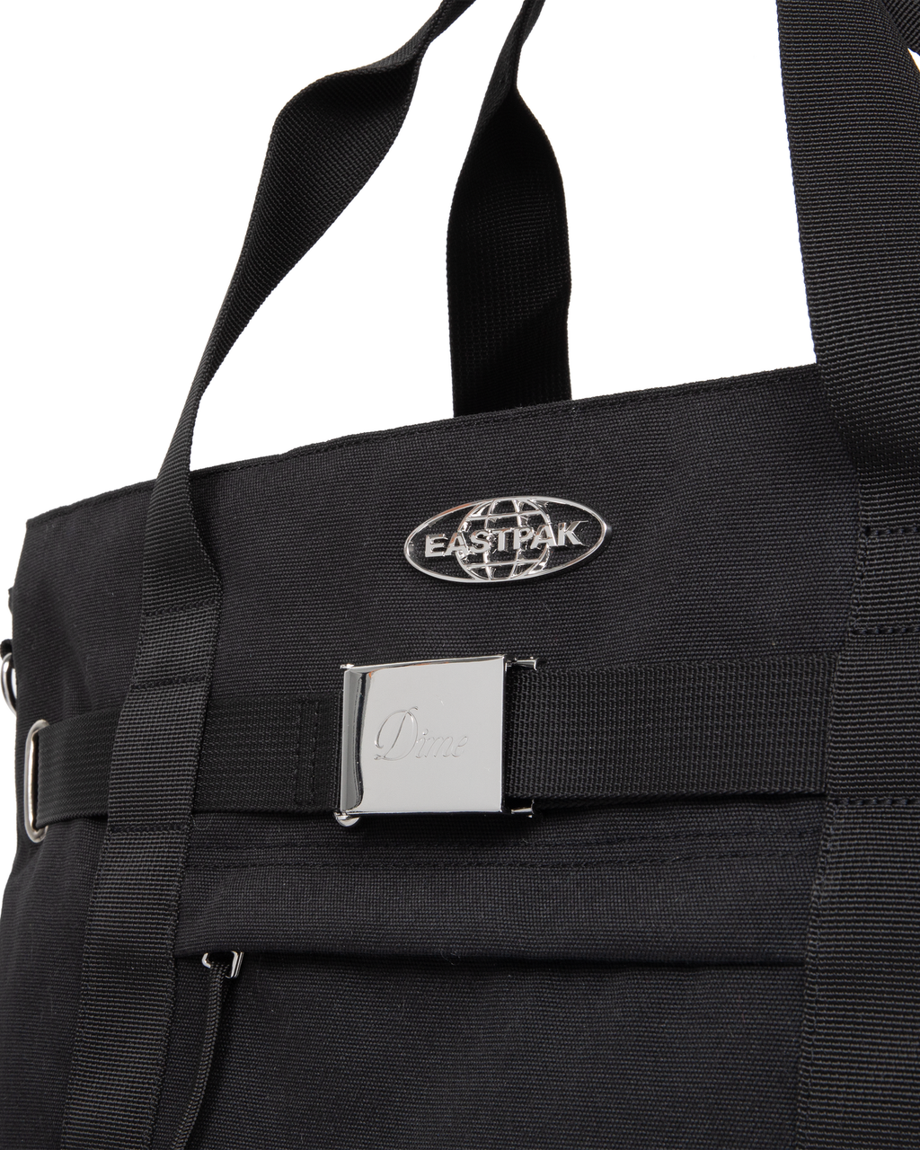Close up of the Eastpak x Dime Skate Tote in Dime Black, showing the chrome Eastpak globe badge above the polished Dime buckle plate on the front webbing strap