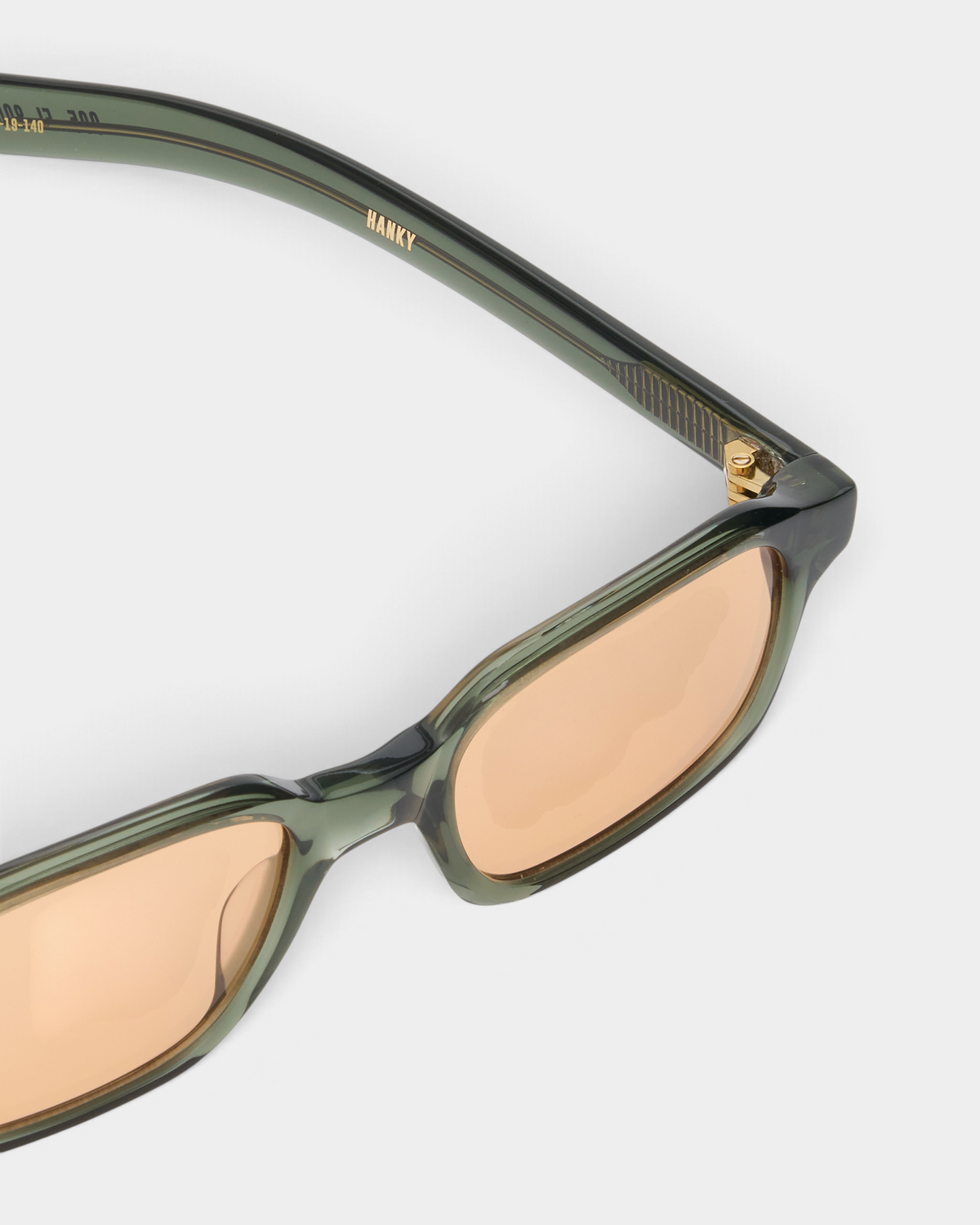 Close-up of the Flatlist Hanky in crystal duck green acetate, showing the hinge, the temple and the faded orange lens