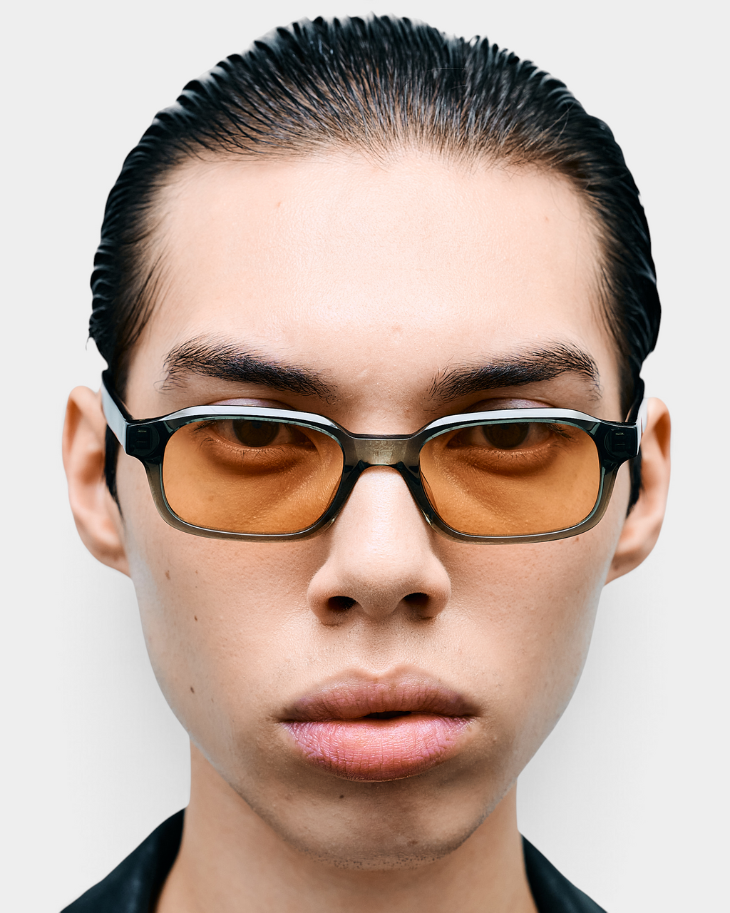 Man wearing the Flatlist Hanky sunglasses in crystal duck green with faded orange lenses, front-facing portrait