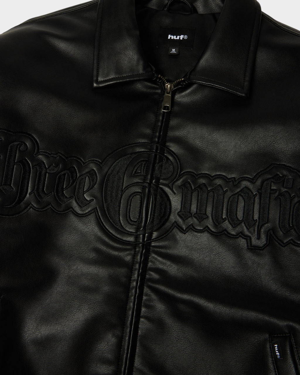 HUF x Three 6 Mafia Jacket - Black, close-up of the collar, zip and embossed three 6 mafia lettering