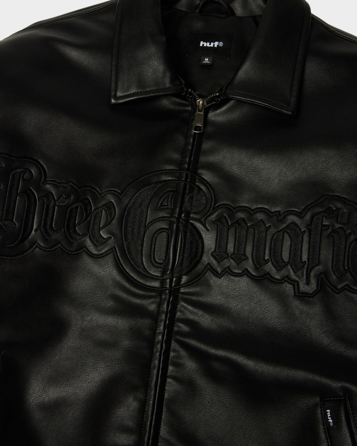 HUF x Three 6 Mafia Jacket - Black, close-up of the collar, zip and embossed three 6 mafia lettering