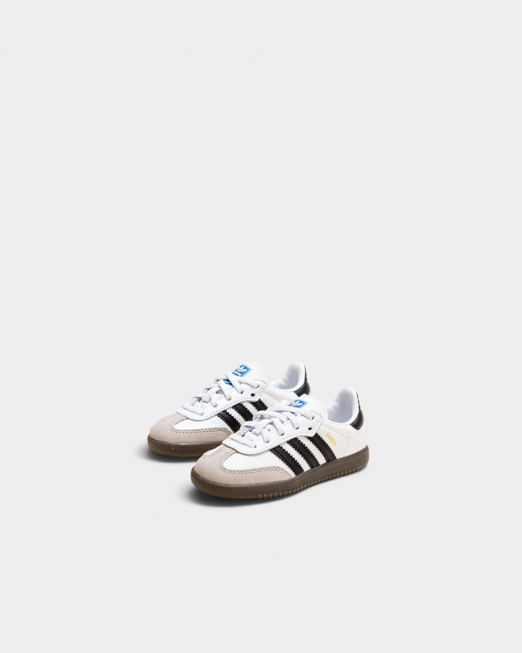 Pair of adidas Kids Samba OG shoes in cloud white and core black on a cream backdrop