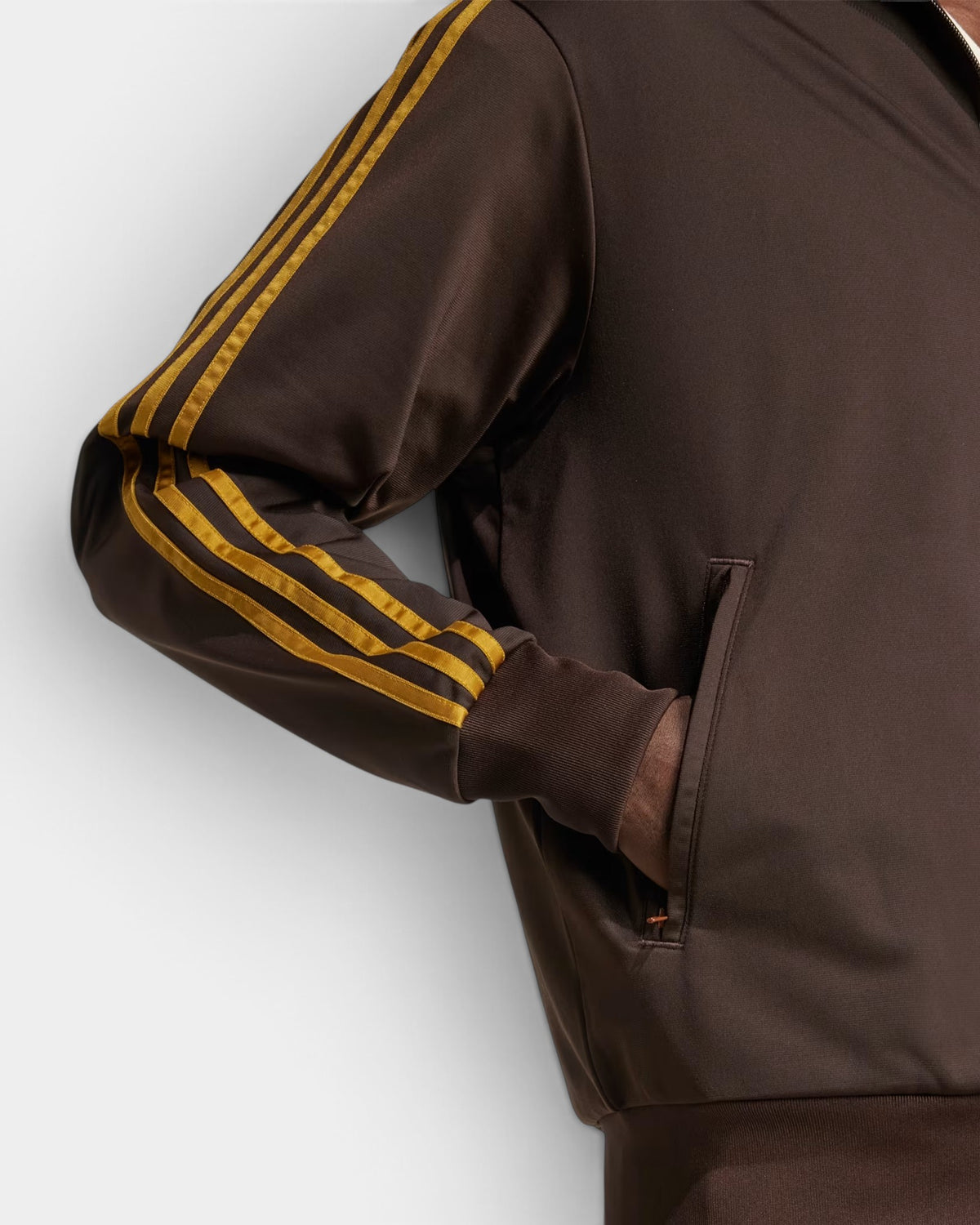 Lockwood Avenue adidas Firebird track top in dark brown with bronze 3-Stripes, featuring a zip pocket and ribbed hem.