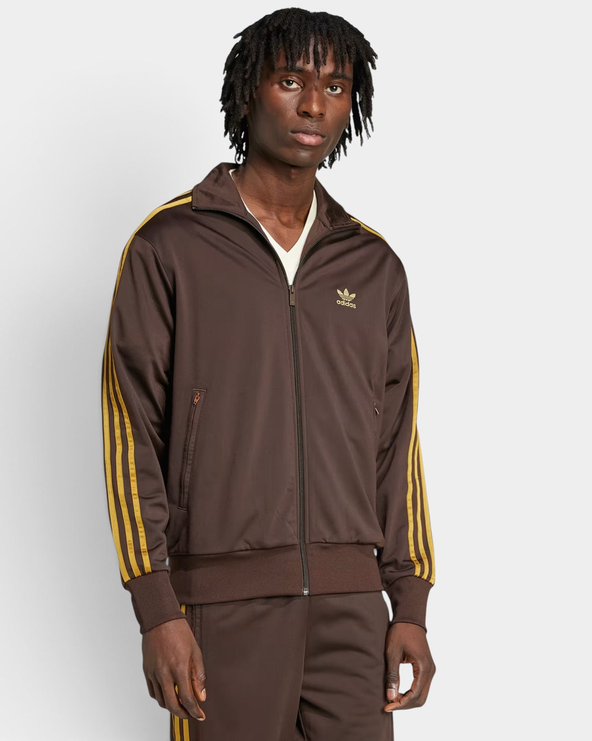 Lockwood Avenue model wearing a dark brown adidas Firebird loose track top with bronze 3-Stripes and zip pockets.