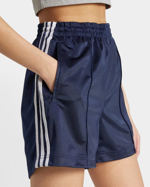 Lockwood Avenue adidas Firebird navy blue tricot shorts with white side stripes and zip pockets on a model