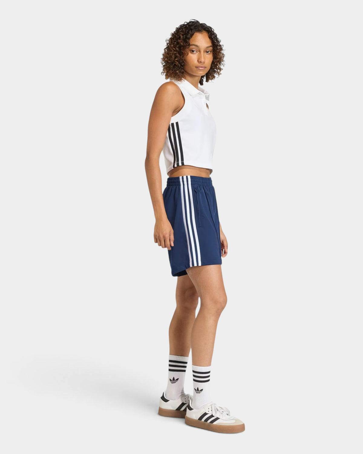 Lockwood Avenue model wearing navy blue adidas Firebird tricot shorts with white 3-Stripes and a mid-rise waist.