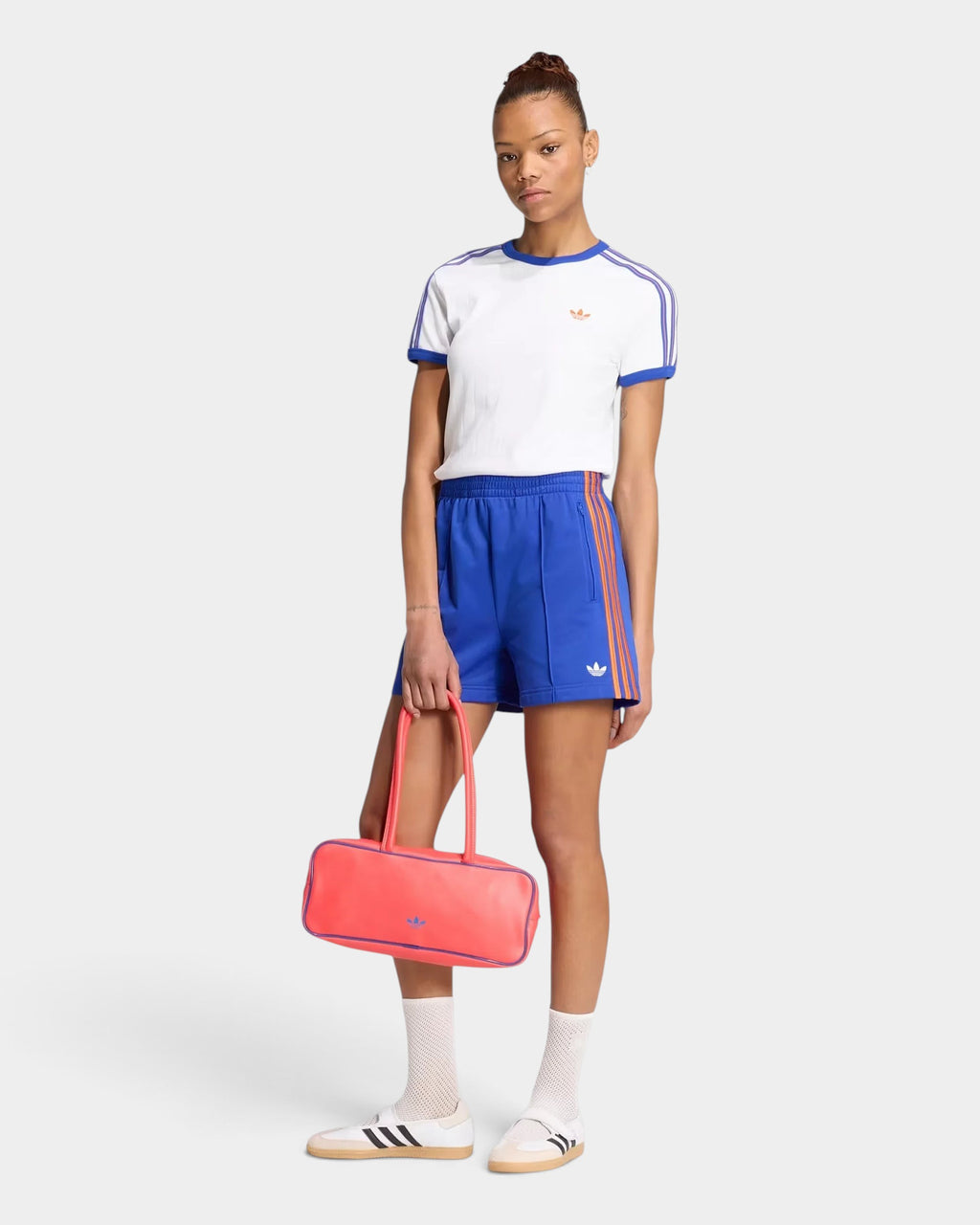 Lockwood Avenue model wearing blue adidas Firebird Classic shorts with 3-Stripes, white t-shirt, and pink handbag.