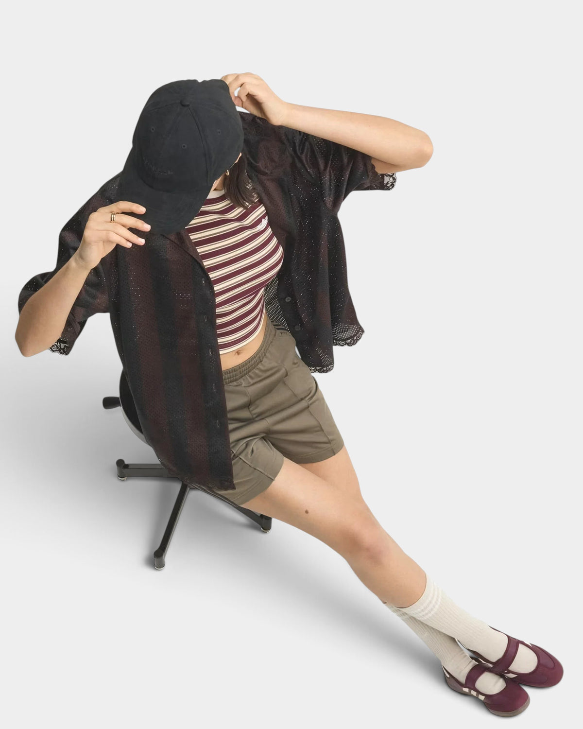 Lockwood Avenue model wearing olive green adidas Firebird Classic shorts with a striped top and black cap