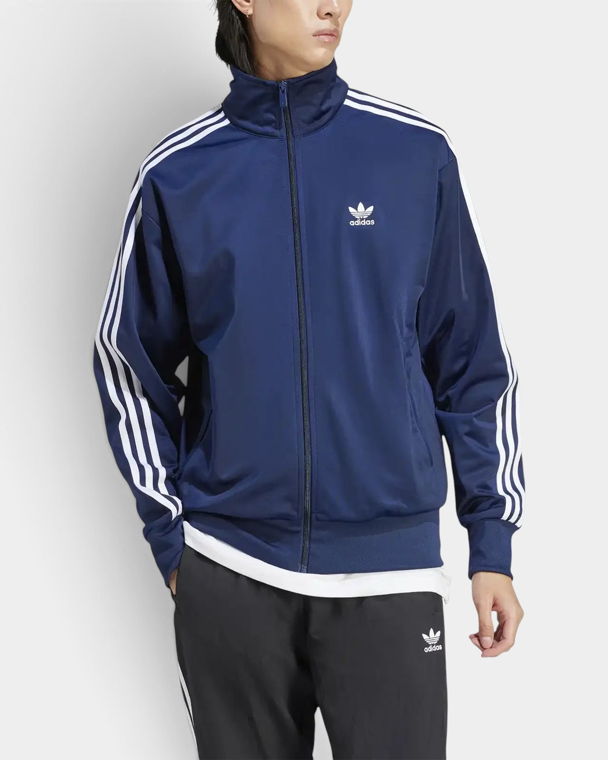 Lockwood Avenue model wearing a night indigo adidas Firebird track top with white 3-Stripes and stand-up collar.